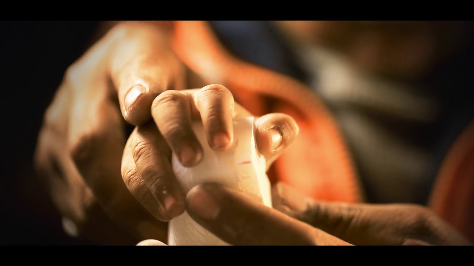 Manos del artesano y su hijo sosteniendo una escultura